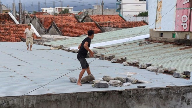 Nguoi dan gia co, chen chong nha cua truoc khi bao do bo. Anh: Thanh Quynh