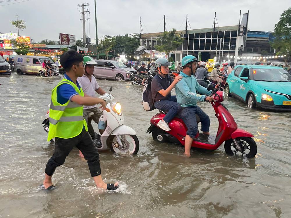 Cac doan vien chia nhau thuc hien phan luong giao thong, huong dan phuong tien di chuyen, ho tro nguoi di xe may, nguoi cao tuoi, dong thoi nhac nho nguoi dan khong chay nhanh, tranh te nga tai khu vuc nuoc ngap. Anh: Minh Tam.