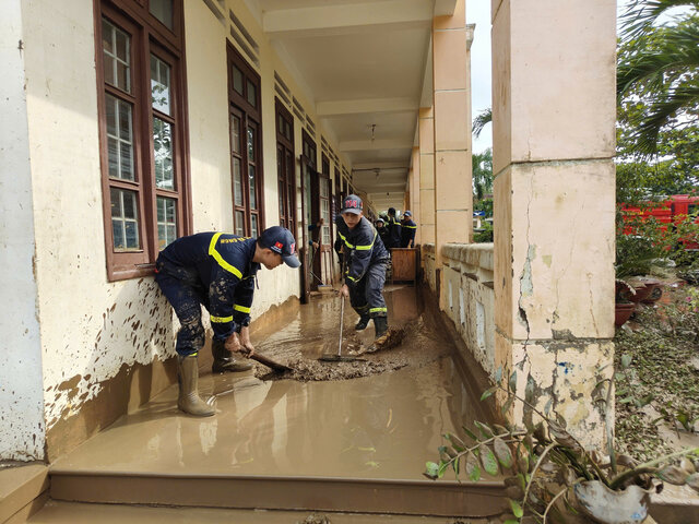 Luc luong chuc nang don dep bun dat o truong hoc sau lu. Anh: Cong an cung cap