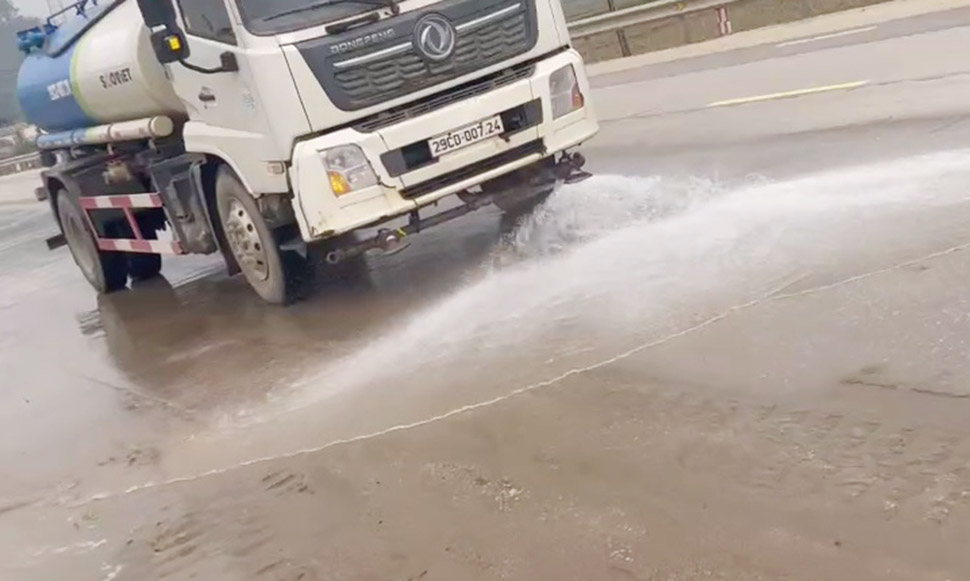 Xe bon tuoi nuoc nham tay rua cat vuong vai tren Quoc lo 1. Anh: Lam Hong.