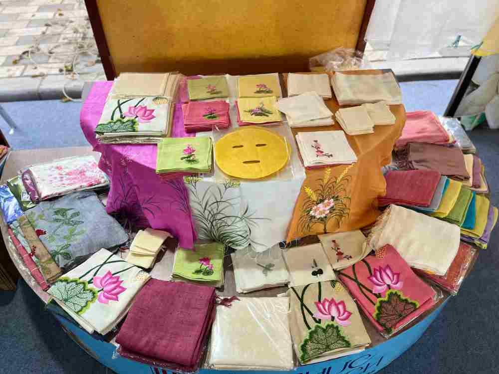 Cac san pham to lua cua Phung Xa duoc trung bay tai le hoi, bao gom vai lua, khan, goi va nhung tam lua in hoa tiet thu cong. Anh: Quynh Mai