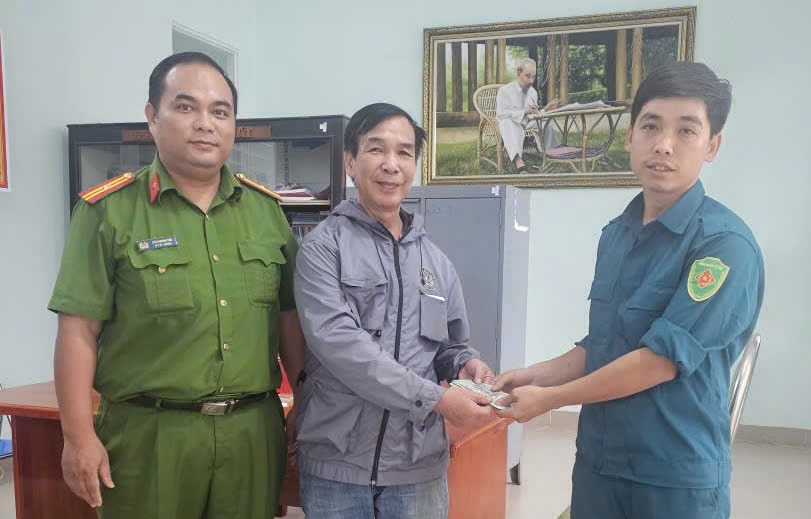 Mr. Nguyen Hoang Hai (middle) received the lost money that the people picked up and asked the police to find the owner to return it. Photo: Provided by the police