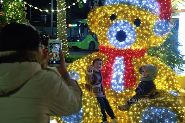 Chi Nguyen Thi Hue (phuong Bach Mai) tranh thu buoi toi cuoi tuan dua 2 con nho di chup anh tai pho Ba Trieu. Chi cho biet, nam nay co nhieu mo hinh trang tri moi la, de thuong khien 2 be nho vo cung thich thu. Chi hi vong day la hoat dong tao nen ki niem dep cho cac be trong mua Giang Sinh.