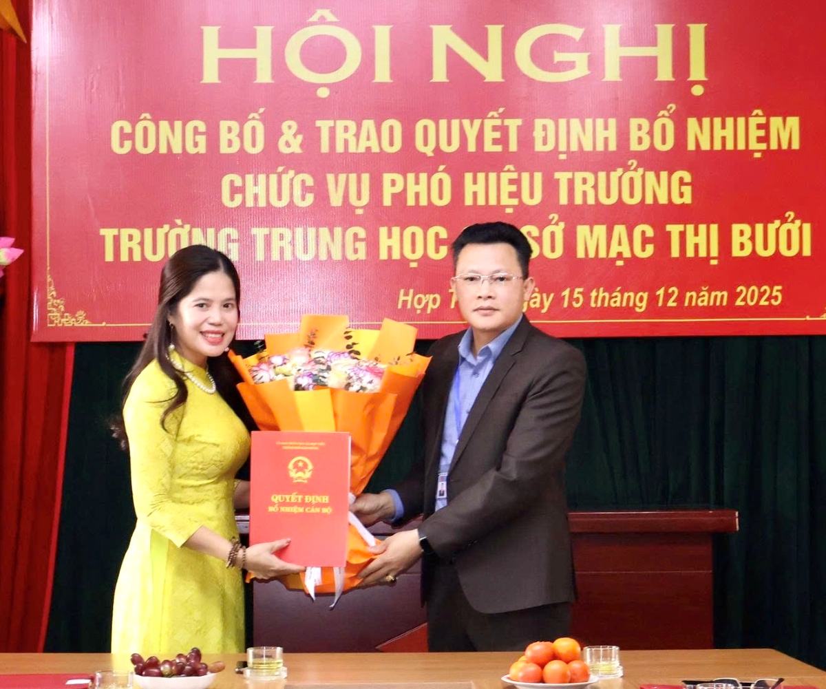 Chu tich UBND xa Hop Tien trao quyet dinh va tang hoa chuc mung ba Tran Thi Lan Huong. Ảnh: Cong TTDT xa Hop Tien