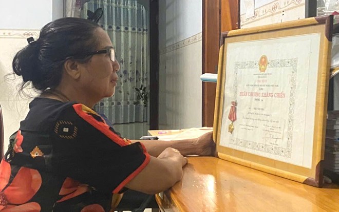 Bà Nguyễn Thị Cúc xúc động trước Huân chương kháng chiến hạng Ba, và đang đợi chờ để nhận Bằng "Tổ quốc ghi công" của liệt sĩ Mai Thị Con. Ảnh: Hưng Thơ.
