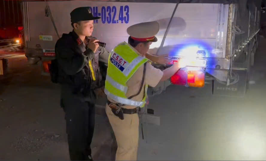 Traffic police of Tay Ninh Provincial Police put up reflective decals with the slogan "Safe home" for trucks and containers traveling at night. Photo: Provided by the police