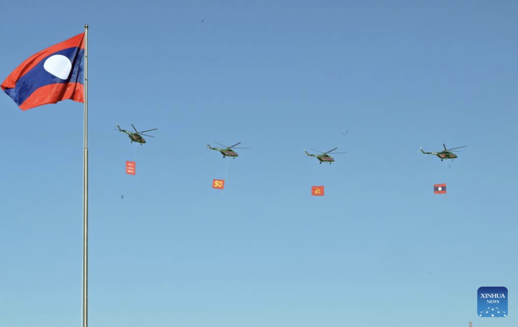 라오스 국경일 50주년 기념 퍼레이드에서 깃발을 든 헬리콥터. 사진: 신화통신