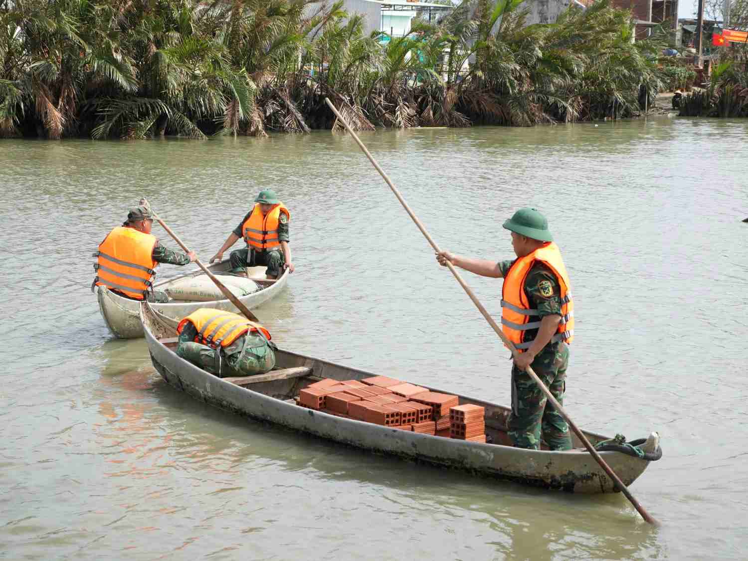 Can bo chien si Trung doan 739 van chuyen vat lieu bang song giup nhan dan xay nha o xa Tuy Phuoc Dong. Anh: Man Duc Dung