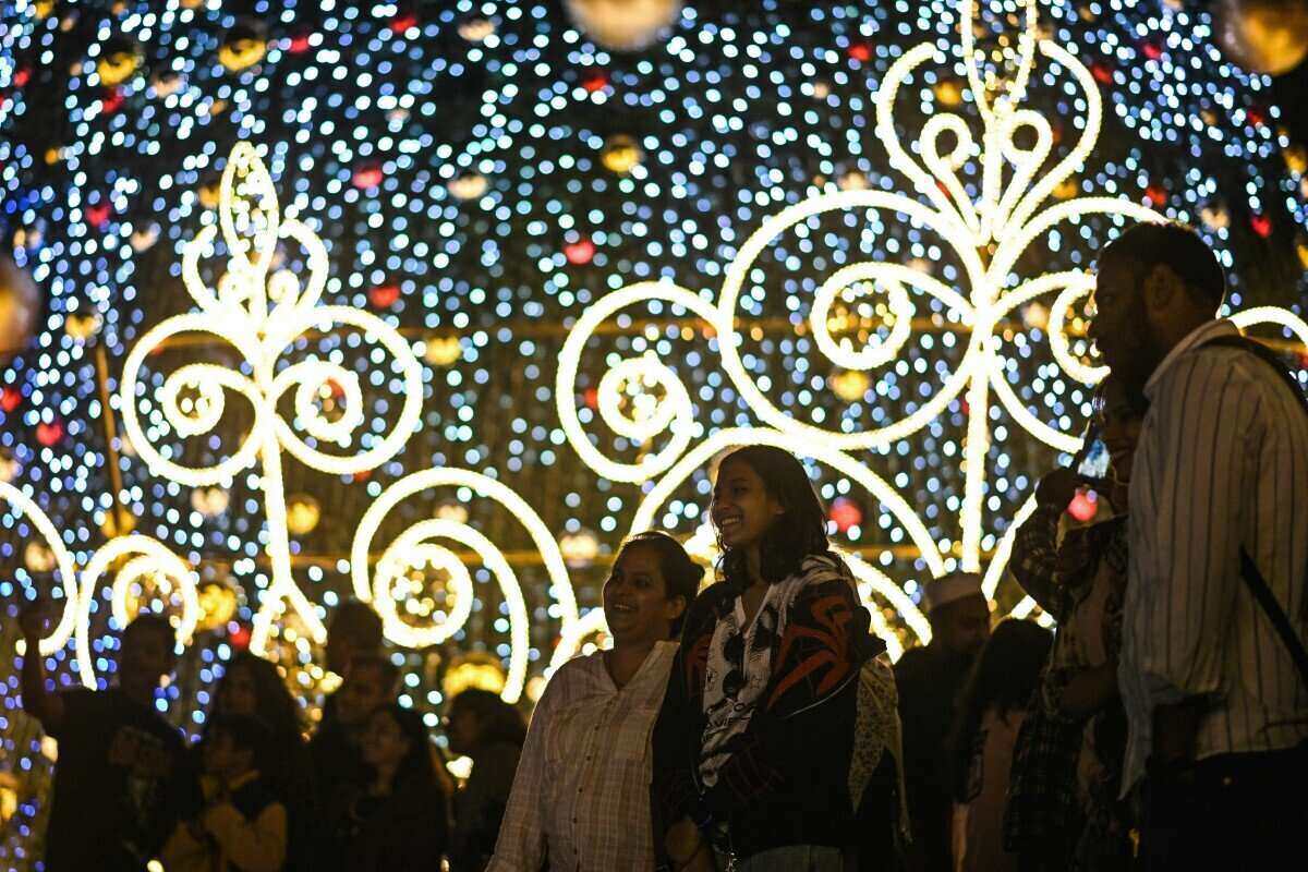 People take photos next to the Christmas tree lit up at Phoenix Mall of Asia in Bengaluru, India on December 23, 2025. Photo: AFP