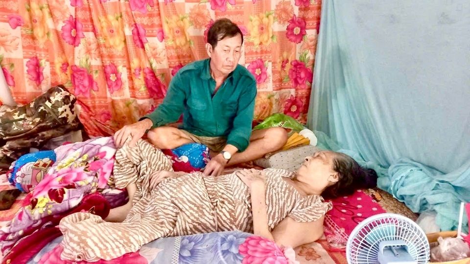 Mr. Nguyen Van Thang calmly held his wife's hand, helplessly watching his partner suffer from cancer. Photo: Hoang Loc