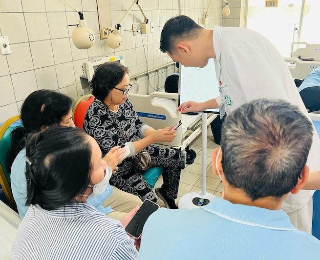 2025년 7월 1일부터 원격 의료 검진 및 치료 가정 검진은 2024년 건강 보험법에 따라 건강 보험 기금(BHYT)에서 공식적으로 지불합니다. 사진은 박마이 병원 간호사가 환자 가족에게 '베트남산' 건강 기록 관리 소프트웨어인 박마이 케어를 사용하도록 안내하는 모습입니다. 사진: BVCC