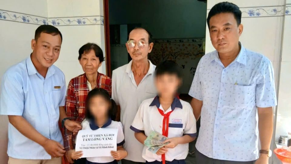 Representatives of the Golden Heart Charity Fund present support money to two orphaned children, so that they can overcome difficulties. Photo: Giong Trom Commune Youth Union.