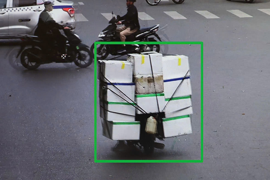 Bulky motorbike carrying goods covers license plate. Photo recorded by AI camera.