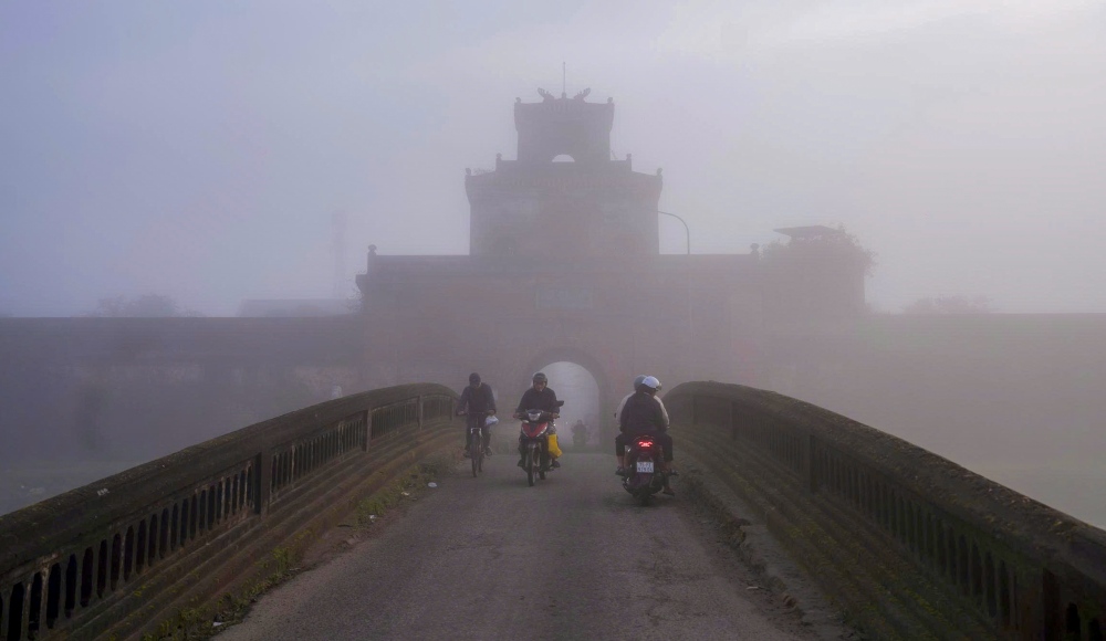 Nguoi dan roi nha di lam tu som. Xe may luu thong cham, trat tu. Nhieu nguoi mac ao khoac day, deo khau trang de tranh suong lanh.
