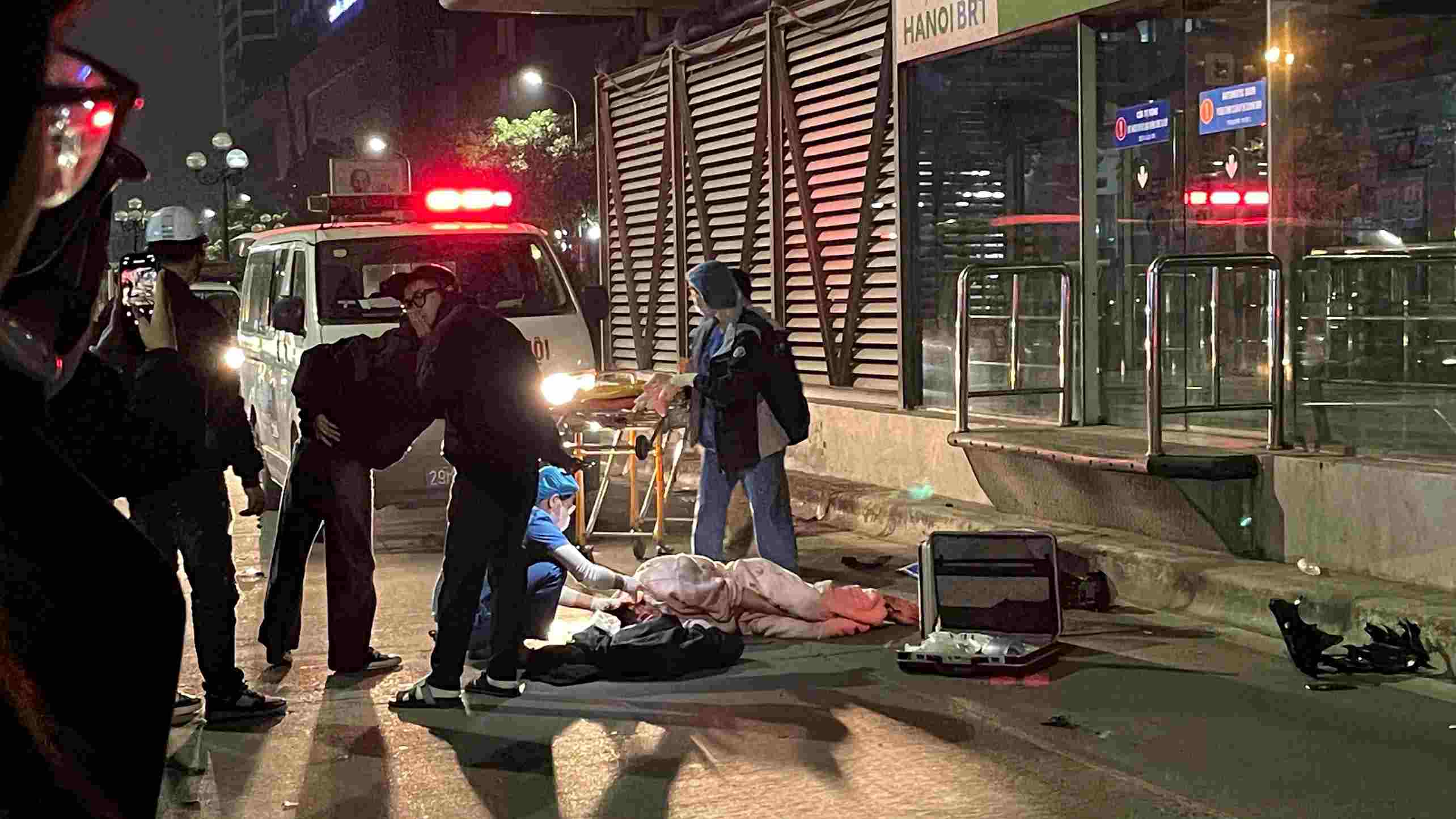 Unexpected accident near BRT waiting station, motorcyclist lying motionless on the road.