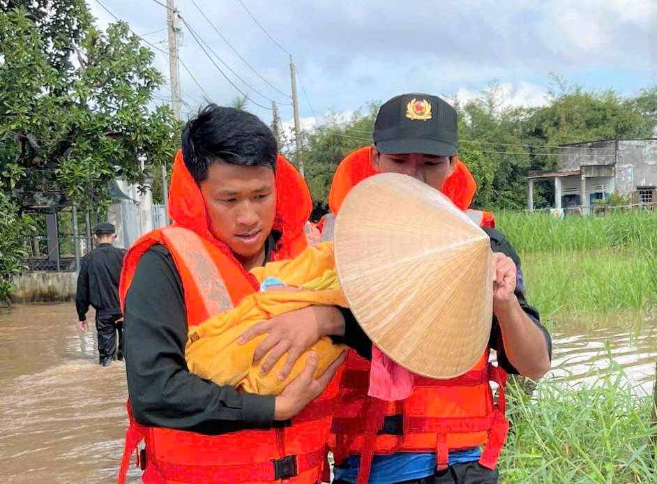 Luc luong cong an vuot lu dua em be mac ket do nuoc lu co lap den noi an toan. Anh: Cong an cung cap