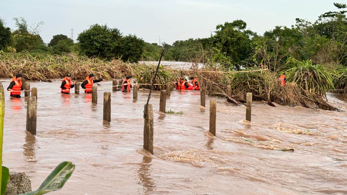 Bám dây để vượt qua dòng nước lũ, tiếp tế đồ ăn cho người dân. Ảnh: Duy Tuấn 