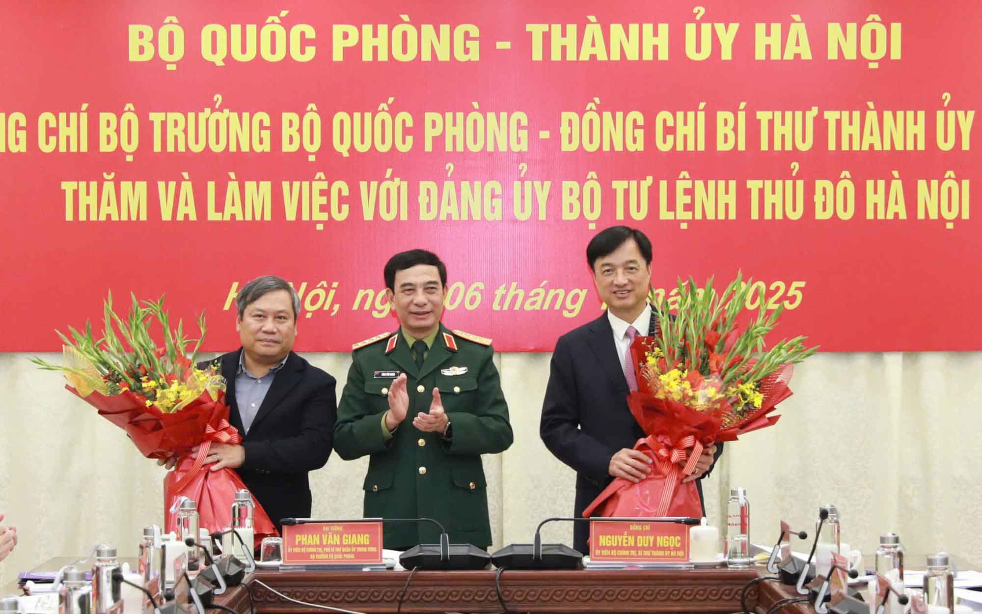 Minister of National Defense Phan Van Giang presented flowers to congratulate Hanoi Party Secretary Nguyen Duy Ngoc and Chairman of Hanoi People's Committee Vu Dai Thang. Photo: Viet Thanh