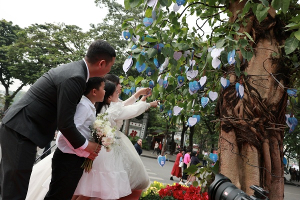Một đôi vợ chồng đưa các con tới tham gia lễ cưới, để các con ghi lại ước nguyện và treo lên cây.