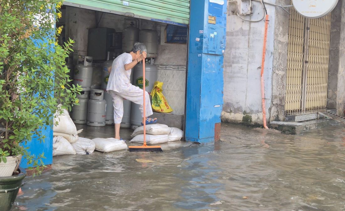 Nhiều hộ dân sống bên đường Phạm Thế Hiển dùng bao cát, ván chắn trước cửa nhà để ngăn nước. Ảnh: Nguyên Chân
