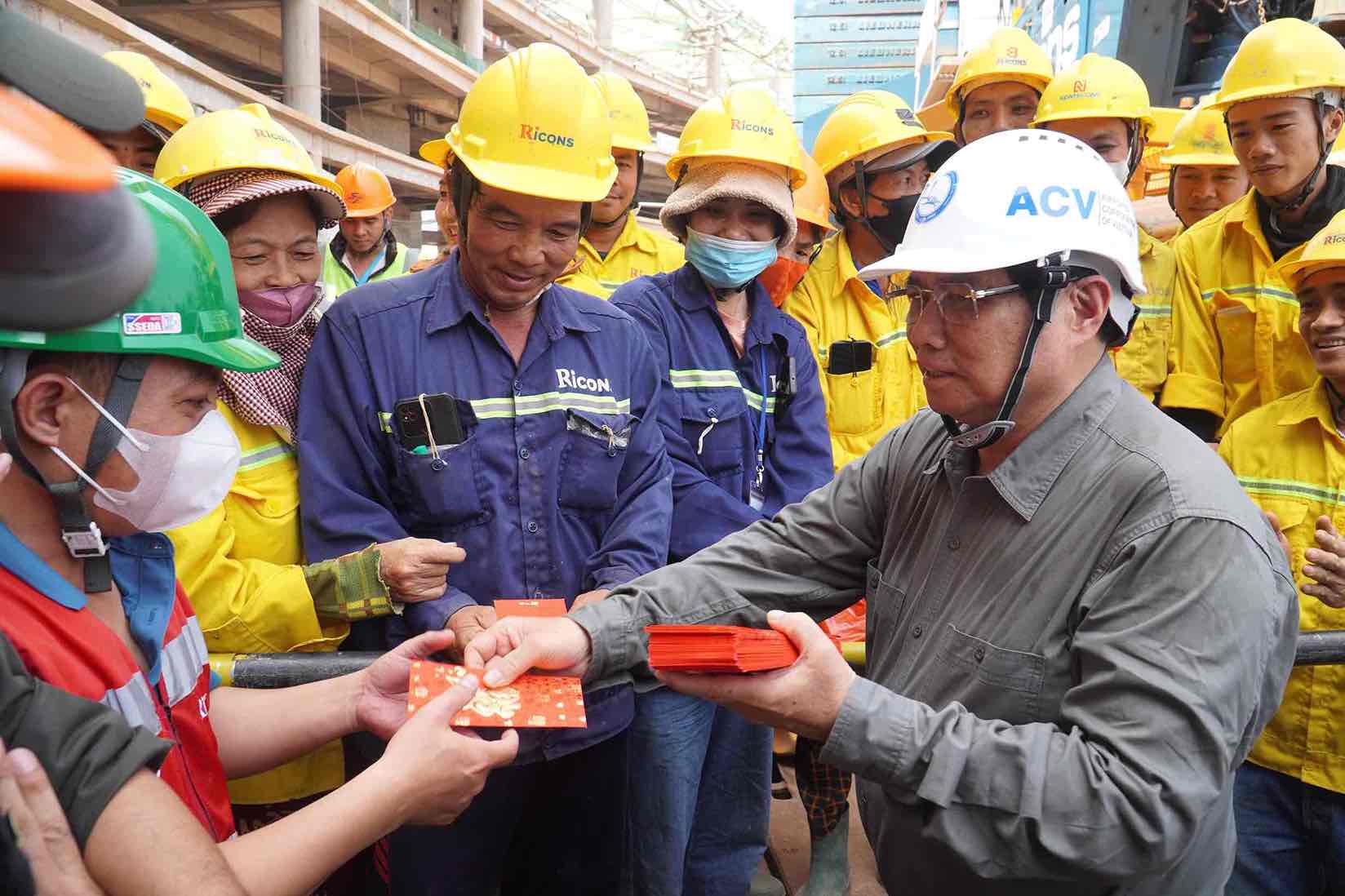 Prime Minister Pham Minh Chinh gives New Year's lucky money to workers who are working through Tet at the passenger terminal of Long Thanh airport. Photo: HAC