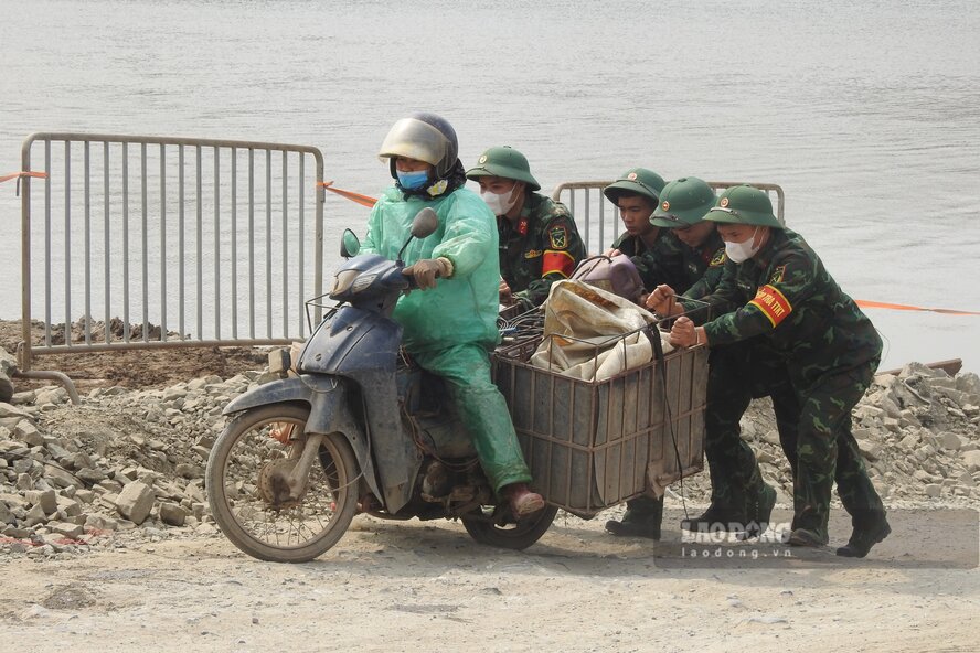 Cac chien si bo doi truc tai cau phao giup do nguoi dan len xuong cau. Anh: To Cong.