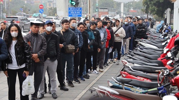 Người dân đội mưa xếp hàng chờ cấp đổi giấy phép lái xe. Ảnh: Minh Hạnh
