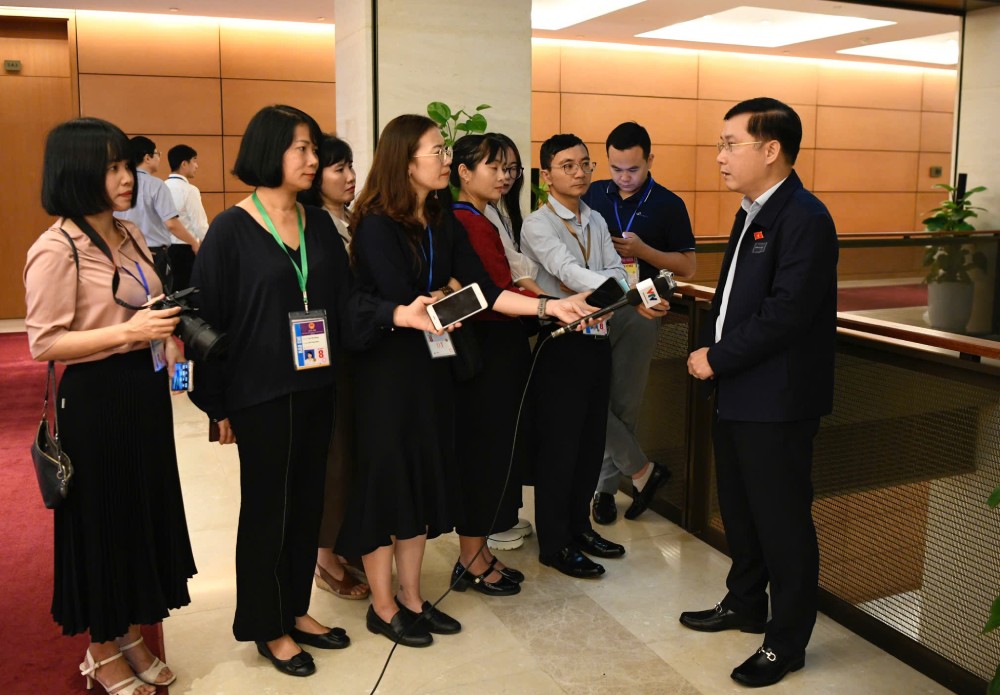 Reporters from press agencies work along the National Assembly corridor. Photo: Pham Dong