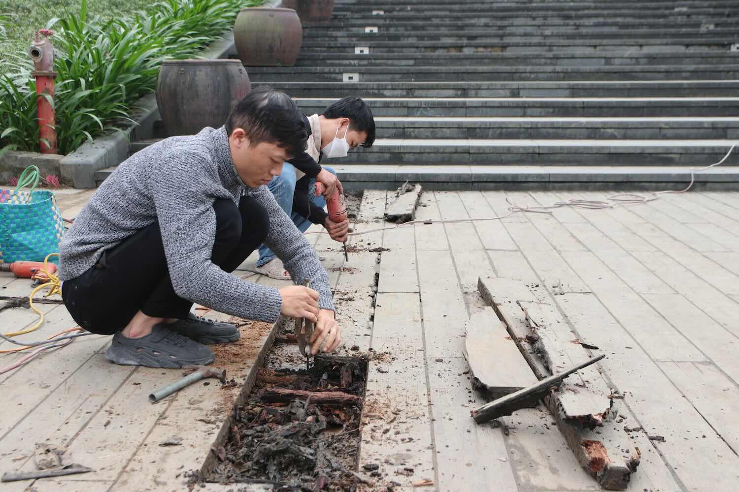 Workers replace damaged sections of the lim wooden bridge. Photo: Nguyen Luan.