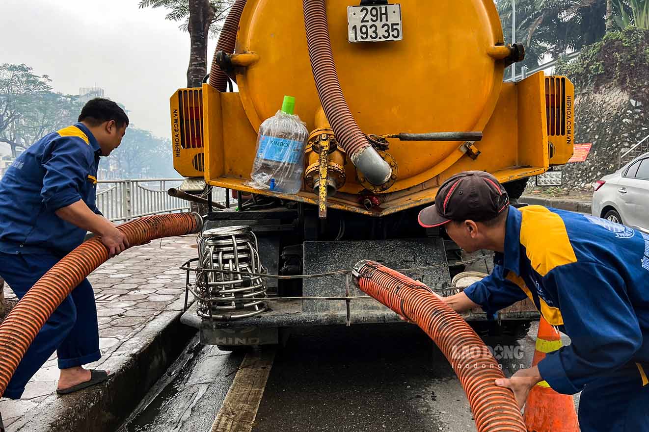 Tren bo, cong nhan dieu chinh he thong duong ong dan bun thai tu duoi long song len xe bon.