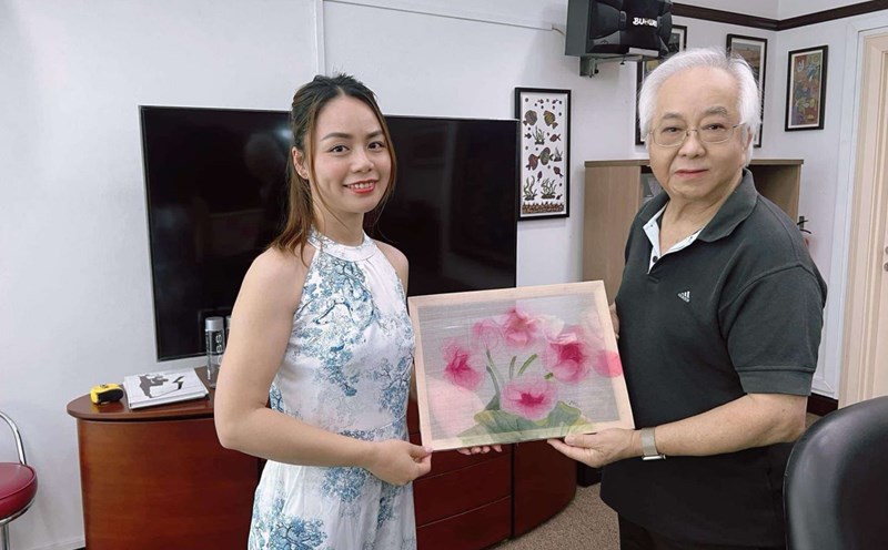 Painter Huong Giang presents paintings to a Singaporean collector who is passionate about Vietnamese folk paintings. Photo: Character provided