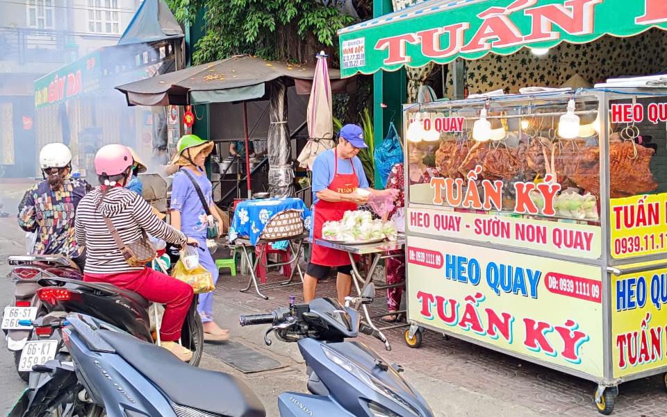 Nhieu nguoi xep hang de mua heo quay cung Than Tai. Anh: Thanh Nghia