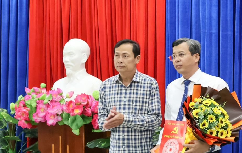 Secretary of the District Party Committee Nam Can Luc Trong Quyen (left) presented the decision to merge the District Party Committee's Propaganda Department and the District Party Committee's Mass Mobilization Committee into the District Party Committee's Propaganda and Mass Mobilization Department to comrade Huynh Viet Trieu, Head of the District Party Committee's Propaganda and Mass Mobilization Department. Photo: Ca Mau Newspaper