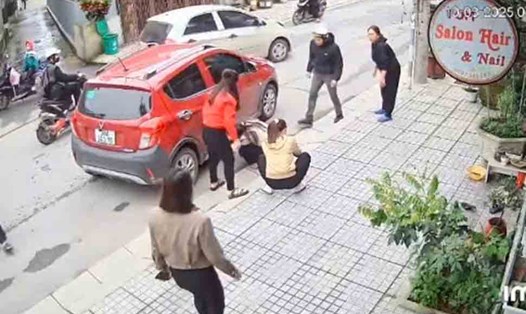 Mọi người xúm lại để đưa cháu bé bị tai nạn mắc dưới gầm xe con ra đưa đi cấp cứu. Tuy nhiên, sau đó cháu bé đã tử vong. Ảnh cắt từ camera.