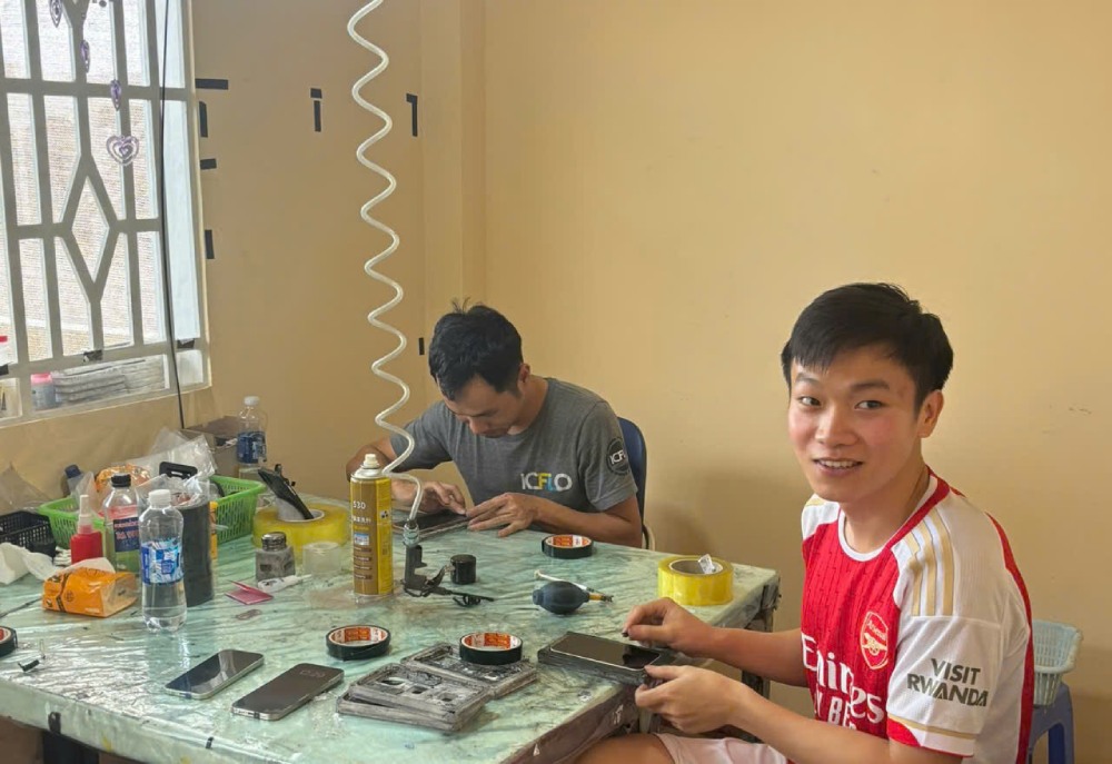 Despite improving his skills in the field of phone repair, Mr. Tu (in red shirt) is still determined to study at a vocational college. Photo: Quynh Chi