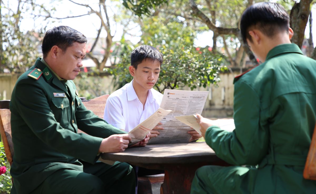 Vu reads the newspaper with the "fathers" wearing green uniforms at My Thuy Border Guard Station. Photo: Hung Tho