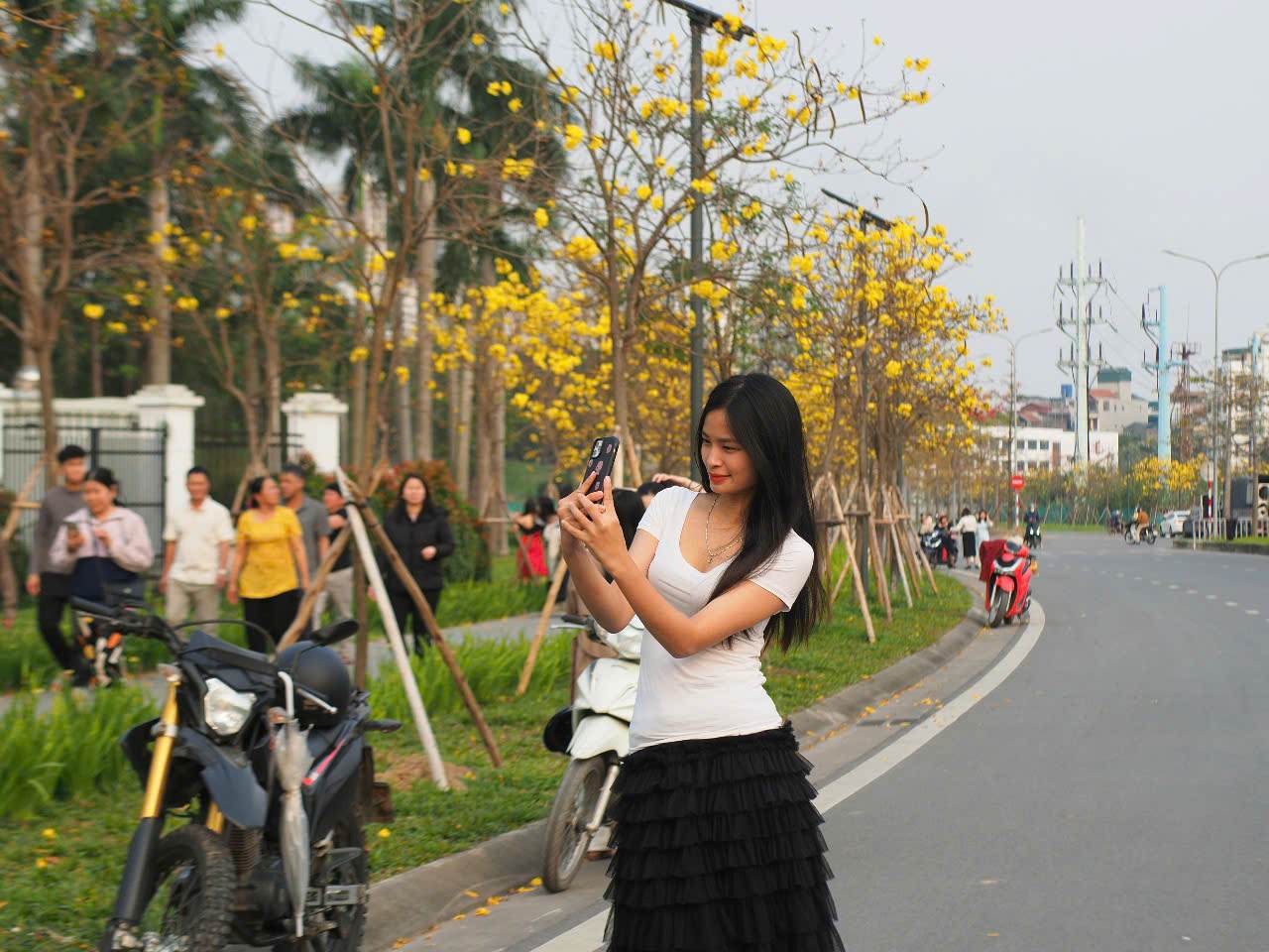 Biet tin hoa phong linh o khu vuc quan Ha Dong no ro, chi Nguyen Phuong Anh (23 tuoi, Dan Phuong) voi vang cung ban be toi day de chup anh. “Khu vuc hoa o day rat nhieu va dep. Khac voi hoa sua, hoa phong linh co sac vang ruc rat cuon hut, mang lai nhung buc anh trong treo, nhe nhang khi dien trang phuc mau trang”.