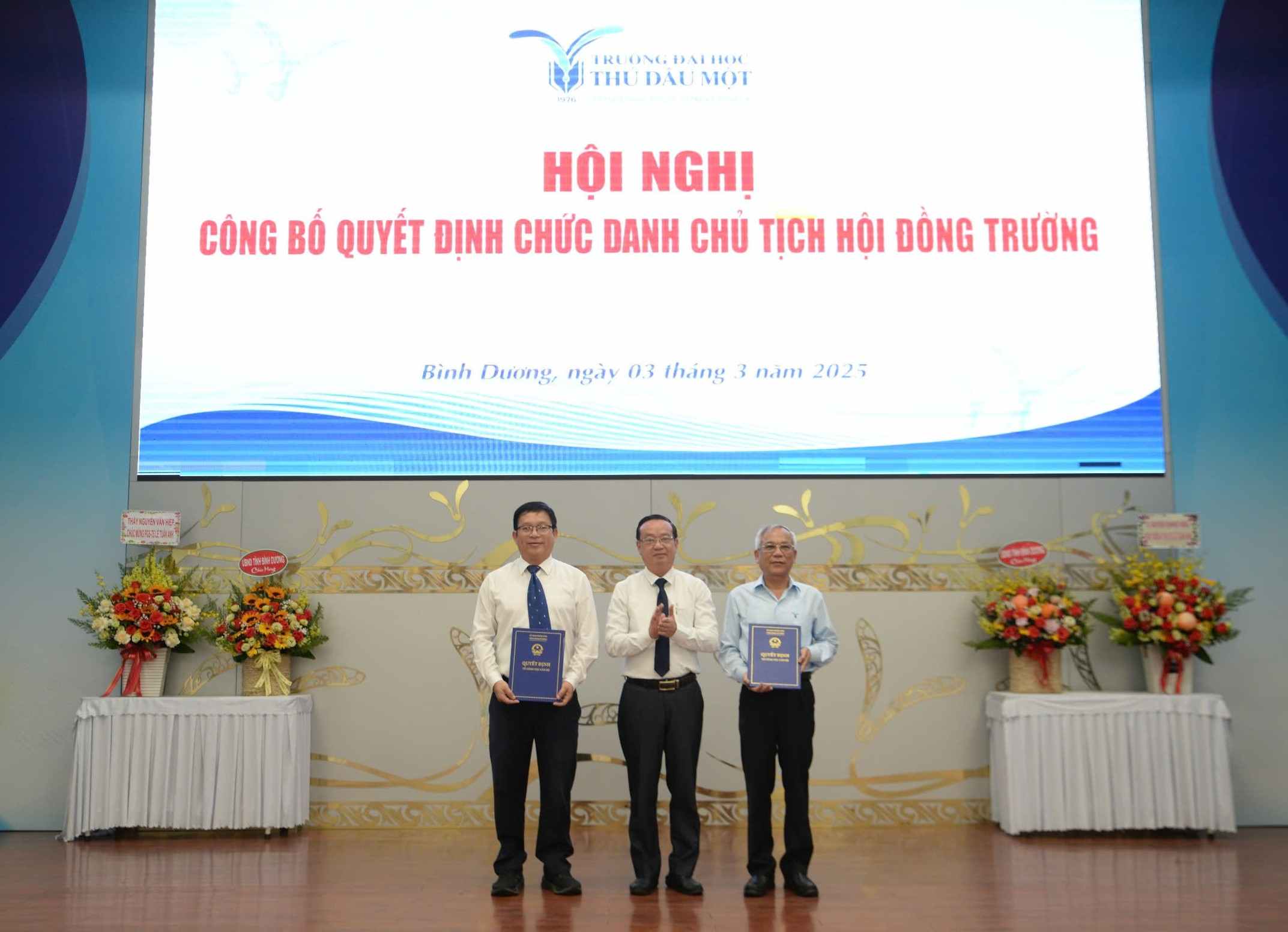 Mr. Bui Minh Thanh - Vice Chairman of Binh Duong Provincial People's Committee presented the decision on early retirement for Mr. Nguyen Quoc Cuong and the decision to recognize Mr. Le Tuan Anh as Chairman of the Council of Thu Dau Mot University. Photo: Thu Dau Mot University