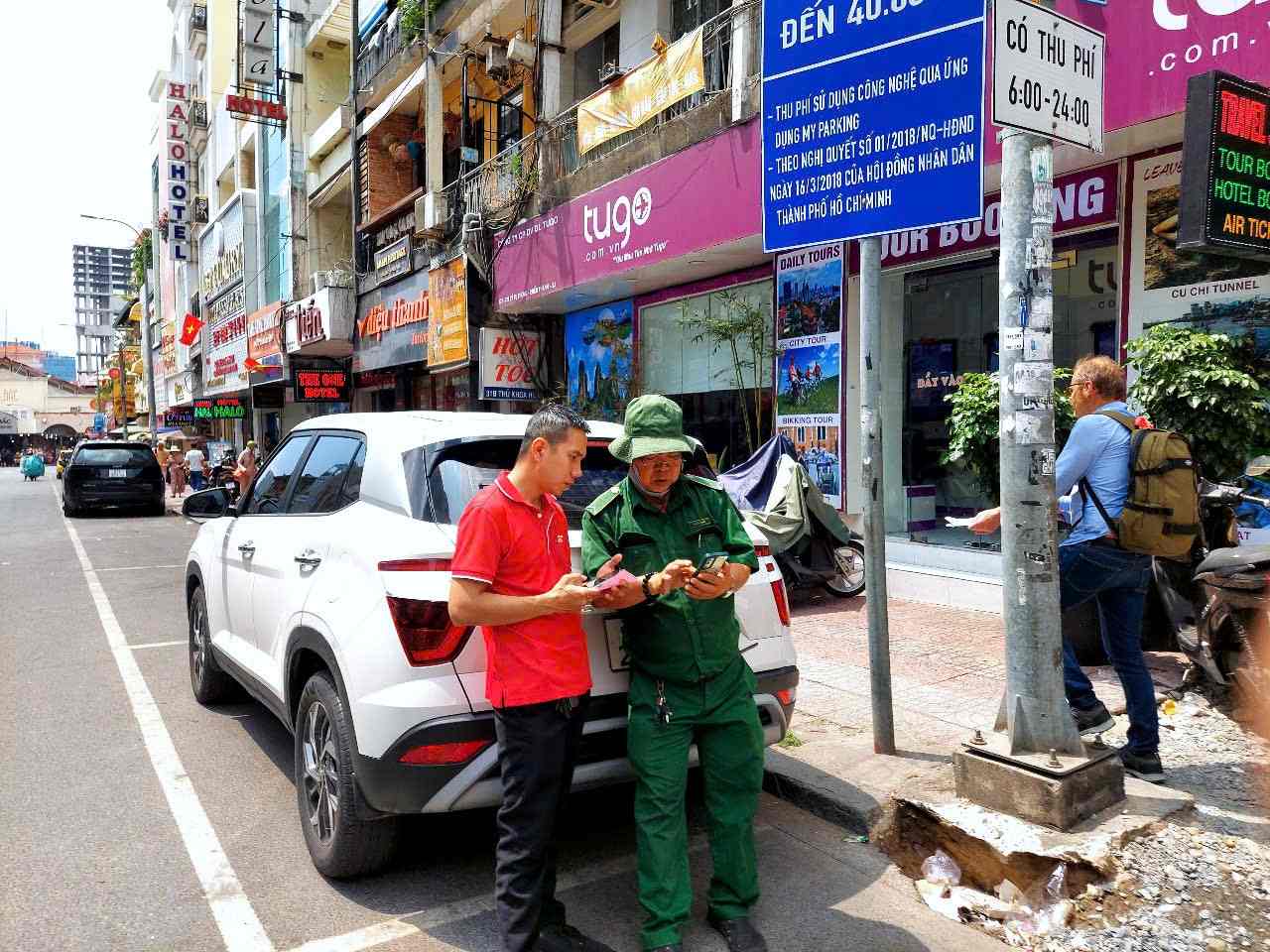 Fee collectors instruct drivers to pay for parking fees on Thu Khoa Huan Street (District 1). Photo: Minh Quan