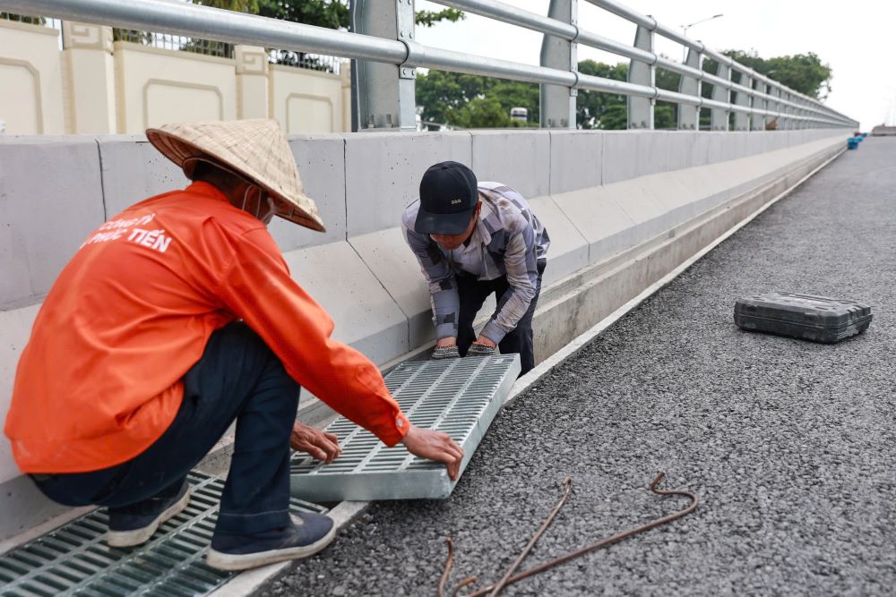 Tren mat cau, cac cong nhan van tiep tuc hoan thien nhung cong doan cuoi cung va ve sinh cong trinh truoc ngay thong xe. Cau co do cao khoang 5 m, duoc chong do bang he thong tru chu T kien co.  