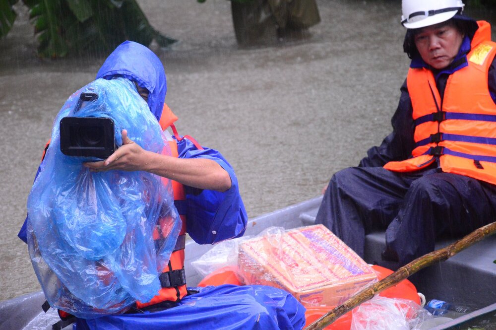 Periodistas de Quang Ngai (izquierda) trabajando en medio de una tormenta. Imagen: La cancion.
