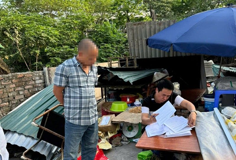 Los oficiales del distrito de Nam Tu Liem transfirieron el aviso de cumplimiento a los hogares en el area para recuperar tierras. Foto: Thanh Long