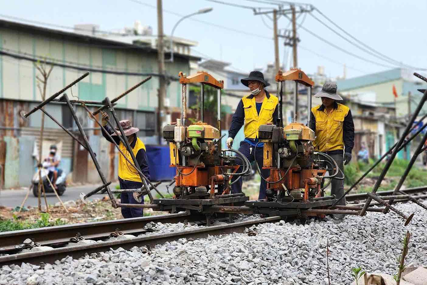 Los trabajadores del ferrocarril de Saigon limpian el medio ambiente, cuidan el ferrocarril de la ruta de los trajes. Imagen de la HAC