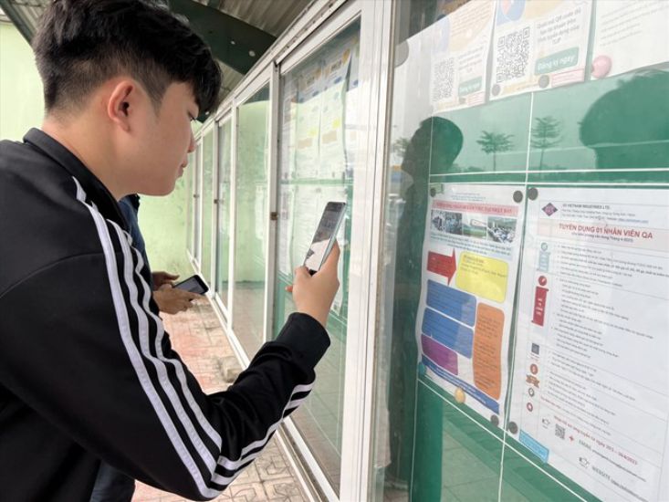 Los trabajadores ven la informacion de la contratacion en el panel de contratacion del Parque Industrial Thang Long, Anh Dong, Hanoi. Imagen de la pagina web de la Universidad de Hong Kong