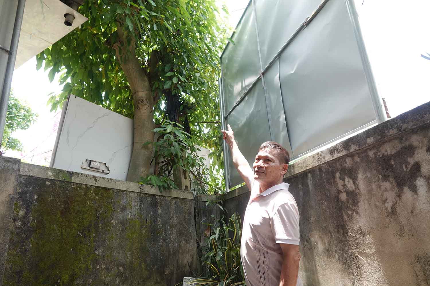 Ông Hoài chỉ lên vị trí cột viễn thông xảy ra chạm chập điện khiến gia đình bị oan số tiền điện đến hơn 9,5 triệu đồng. Ảnh: Trần Tuấn.