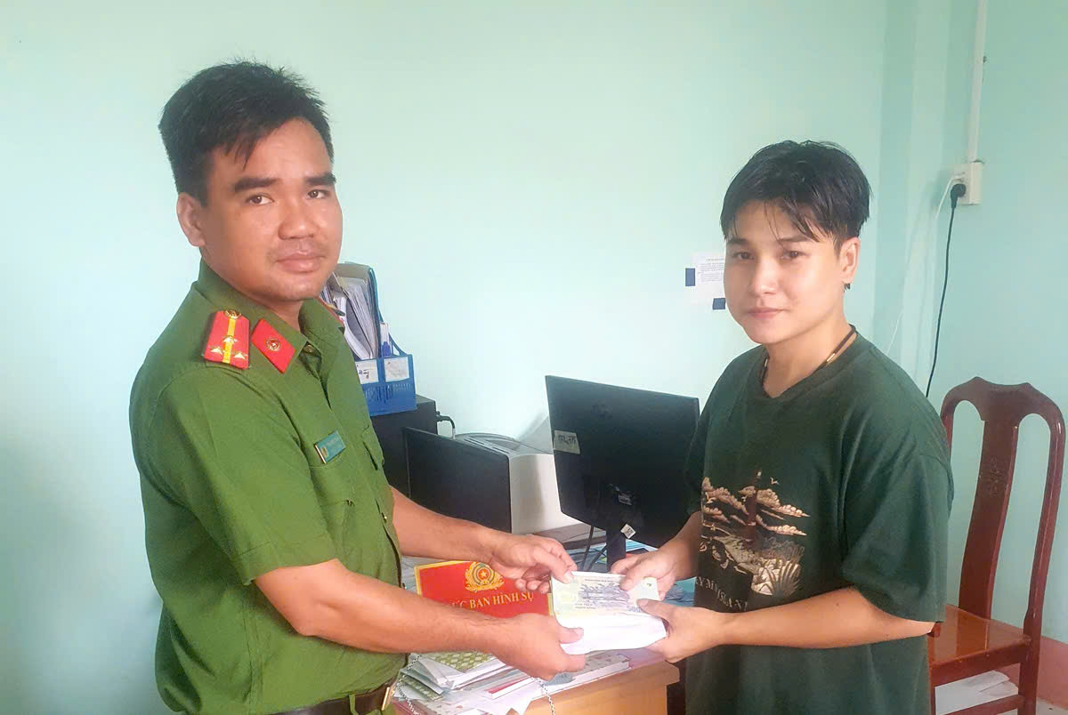 Anh Tạ Minh Lộc bàn giao số tiền nhặt được cho công an để trả lại người đánh rơi. Ảnh: Công an cung cấp