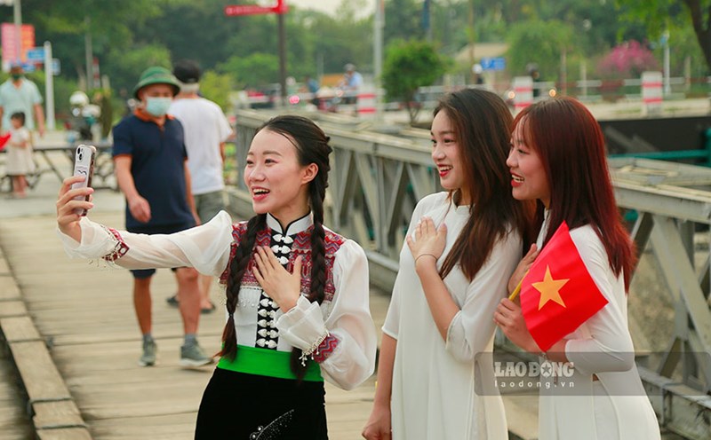 Young people carry the national flag, posing for photos to celebrate the anniversary of the historic Muong Thanh bridge. Photo: Quang Dat