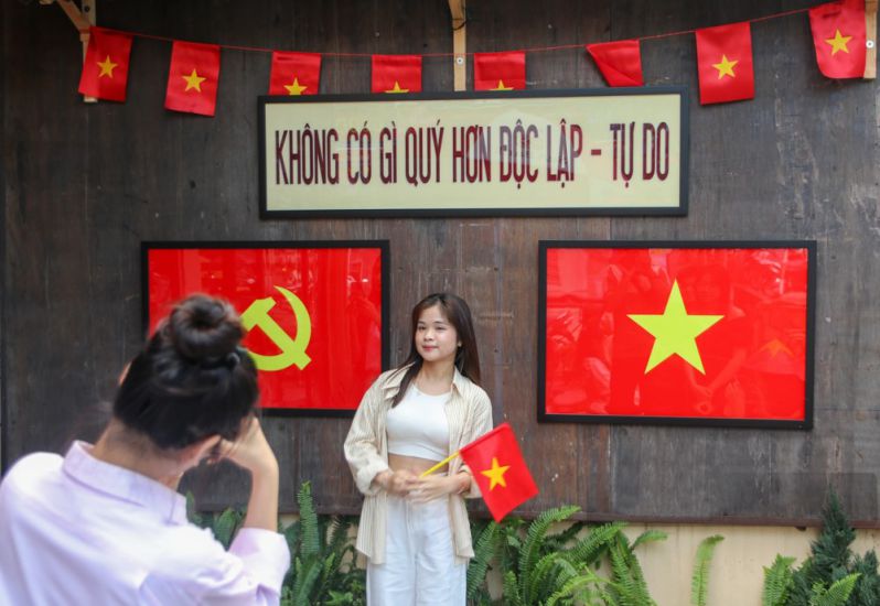 Jovenes con bandera nacional toman fotografias en Hue para celebrar el 50 aniversario de la liberacion del sur y la unificacion del pais. Imagen de la pagina web de la organizacion