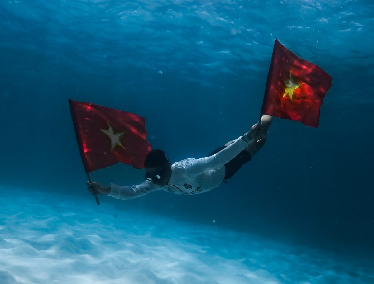 Den Phu Quy, du khach thuong trai nghiem lan bien, ngam san ho. Tuy nhien dip le 30.4 nay, nhieu ban tre lan bien cung la co to quoc tren tay de chup anh duoi nuoc, the hien tinh yeu bien dao to quoc.  Anh: Huan Phu Quy
