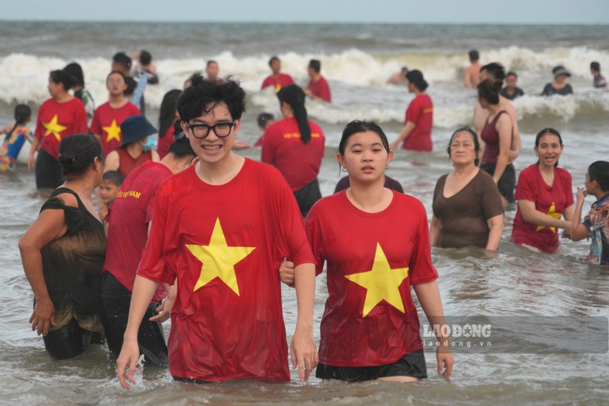 Nu cuoi ron rang tren bai tam, trong mau ao co To quoc. Anh: